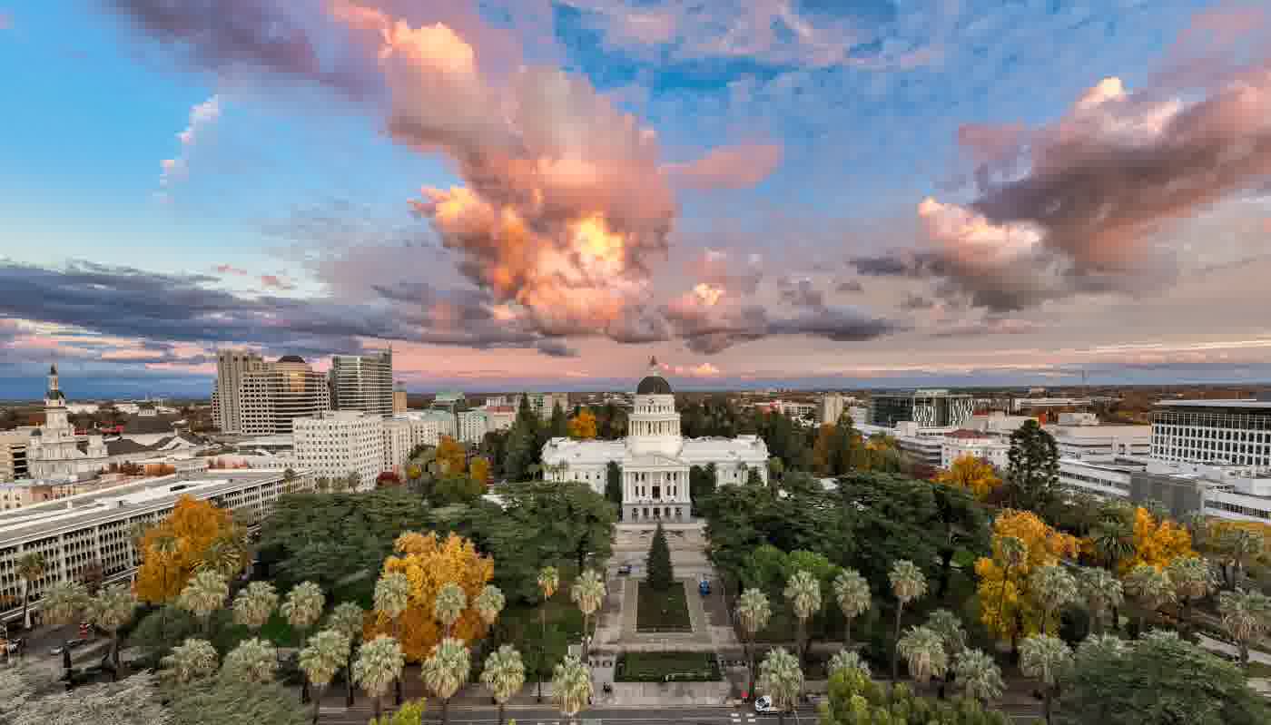 Aerial view of a California city skyline at sunset with autumn trees